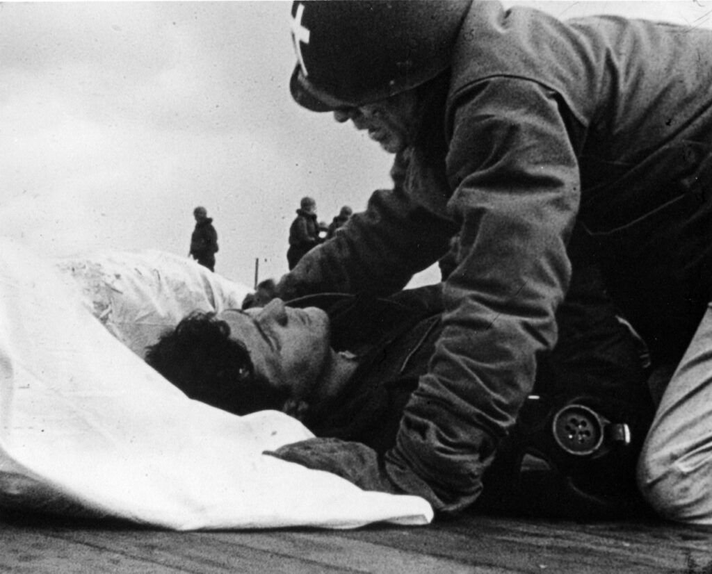 Father O'Callahan tends to a wounded man on the flight deck of the USS Franklin. Credit: Naval History and Heritage Command