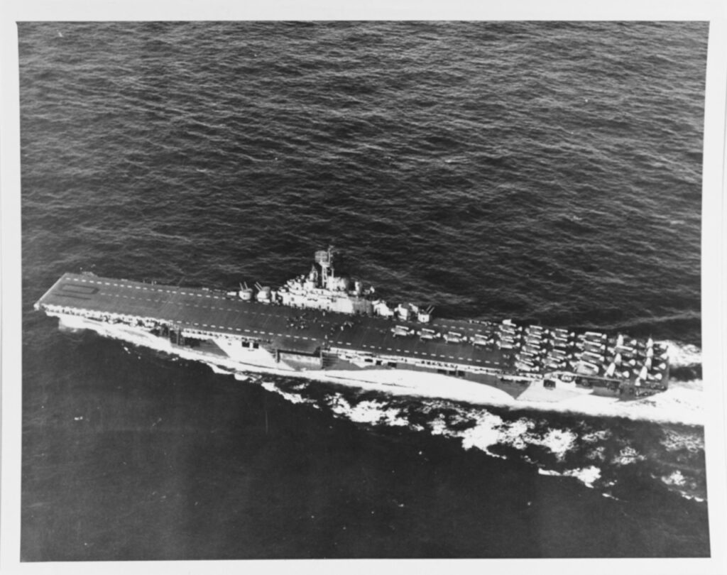 USS Yorktown, CV-10, shown underway in June 1944 during the Marianas campaign. The photo is taken from a plane flying off her port side. The ship is painted in camouflage Measure 33, Design 10a. There are twenty-eight aircraft parked on her flight deck aft with folded wings. Photo credit US National Archives 80-G-238298