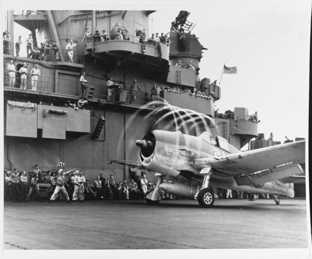 A Grumman F6F-3 Hellcat fighter makes condensation rings as it awaits the take-off flag aboard USS Yorktown (CV-10), 20 November 1943. The plane is from Fighting Squadron Five (VF-5). Yorktown was then hitting targets in the Marshall Islands to cover the landings in the Gilberts. VF-5 would serve onboard Franklin in 1945. By that time, flying Corsairs.