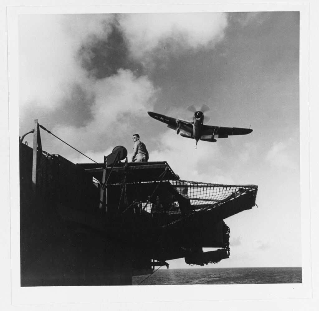 Photo taken below flight deck level showing A Curtiss SB2C-3 "Hell-diver" bomber taking a "wave-off" while attempting to land in March 1945. Landing signal officer's platform is in the foreground