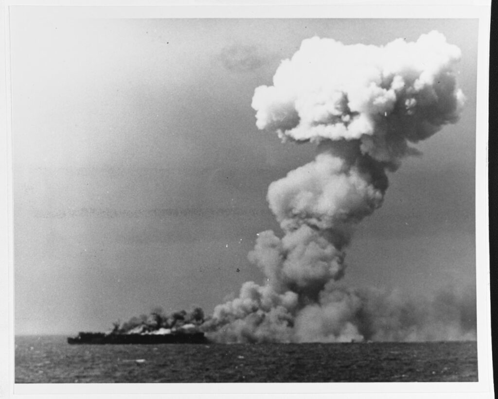 Photo taken from a distance showing a mammoth pillar of smoke rising from USS Princeton afte a Japanese bomb exploded below decks.