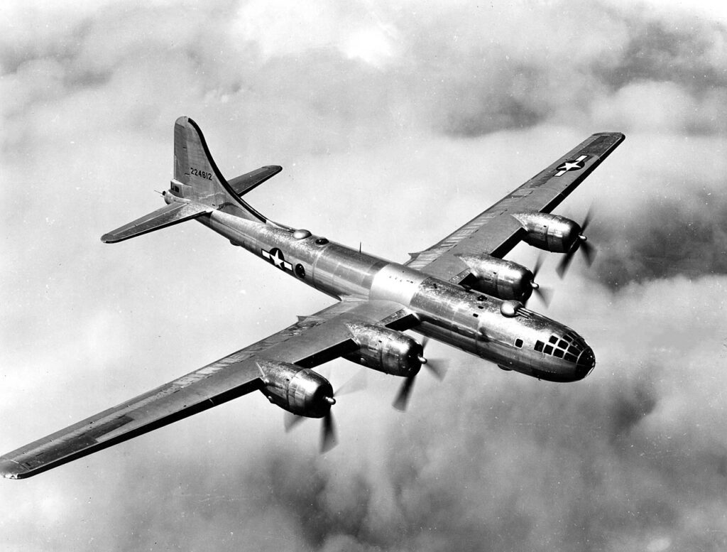 A B-29 is shown flying over clouds. This B-29 was delivered to the 504th Bombardment Group on 1 November 1944. Named Miss Su Su after the granddaughter of the crew commander, Major A. Sidney Hale.