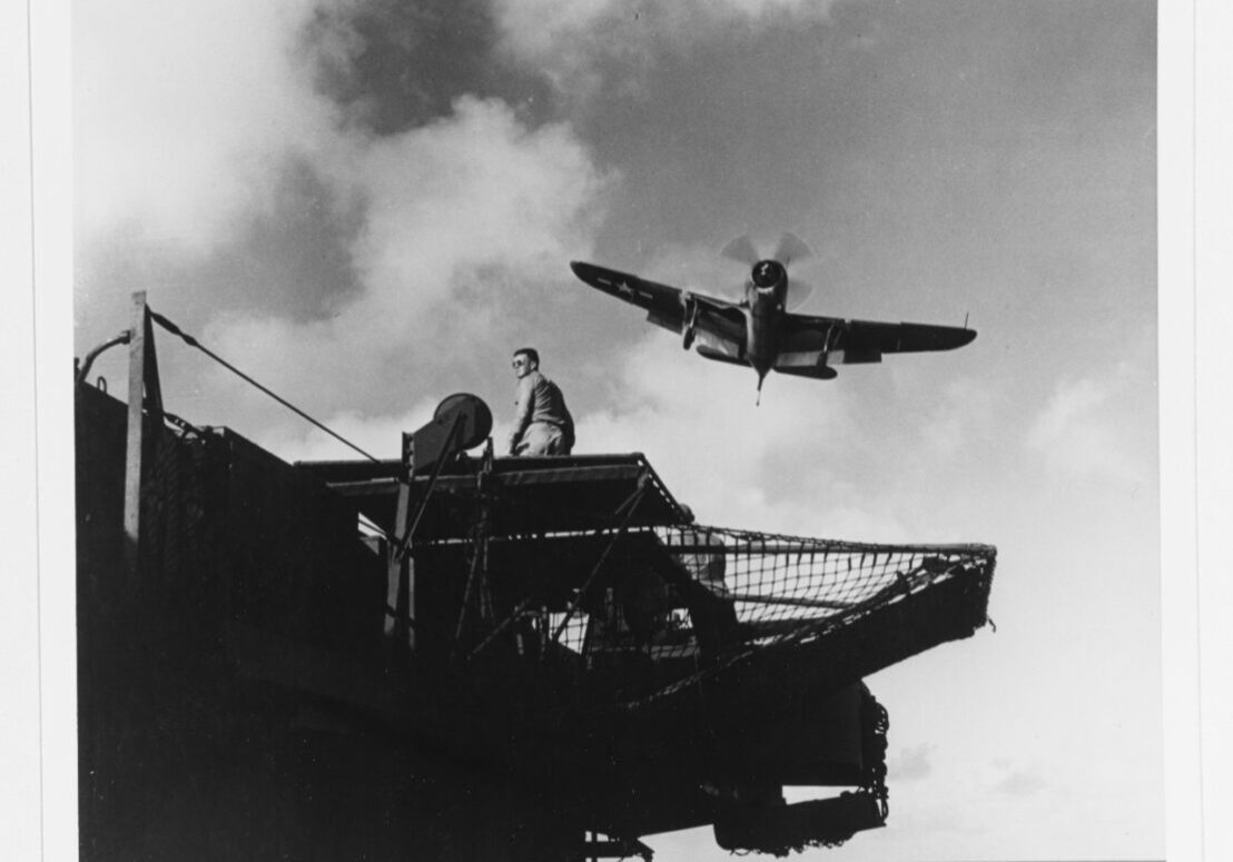 Photo taken below flight deck level showing A Curtiss SB2C-3 "Hell-diver" bomber taking a "wave-off" while attempting to land in March 1945. Landing signal officer's platform is in the foreground