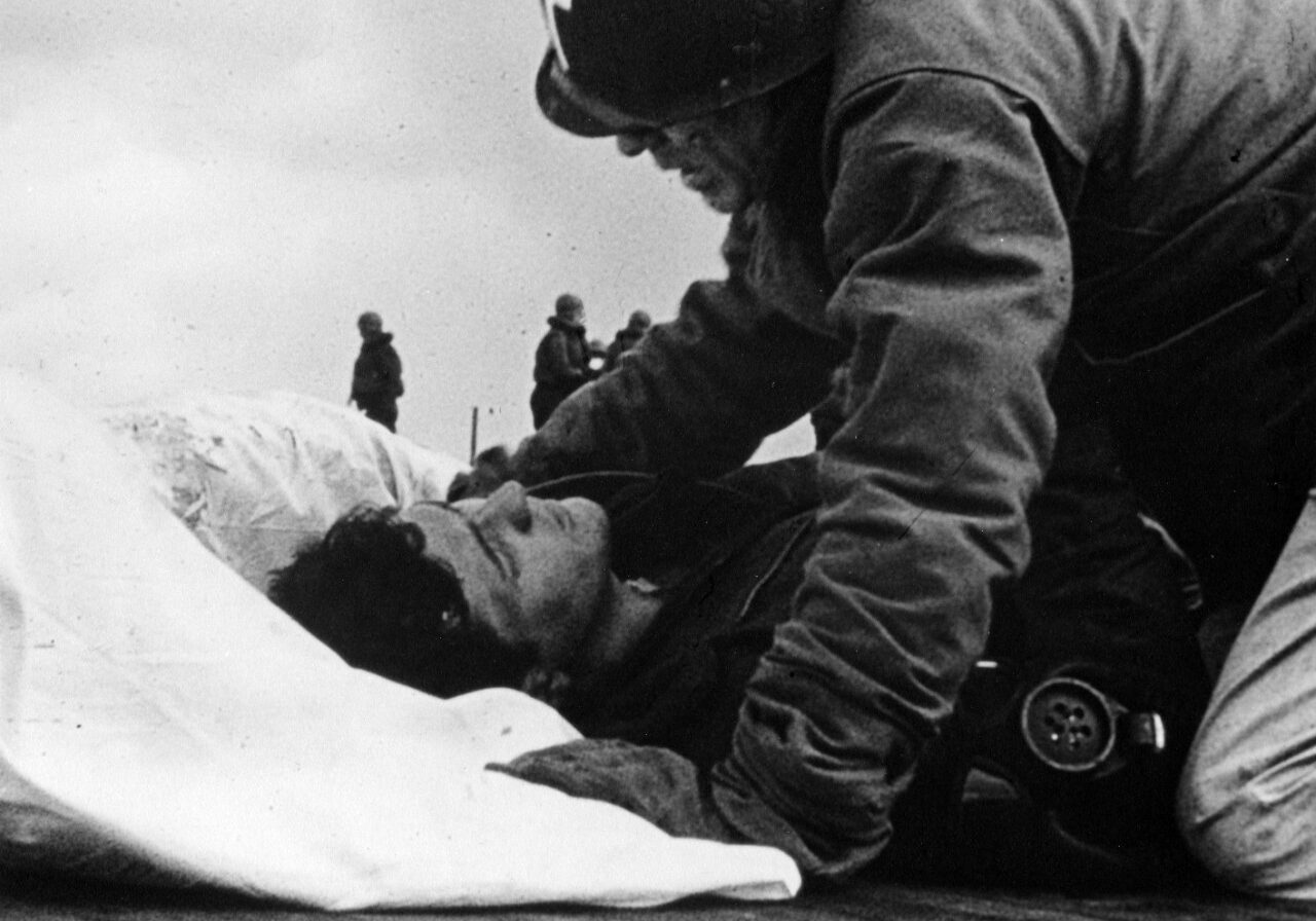 Father O'Callahan tends to a wounded man on the Franklin's flight deck. Credit: Naval History and Heritage Command