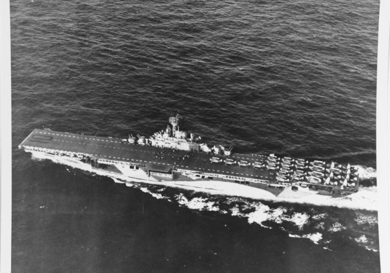 USS Yorktown, CV-10, shown underway in June 1944 during the Marianas campaign. The photo is taken from a plane flying off her port side. The ship is painted in camouflage Measure 33, Design 10a. There are twenty-eight aircraft parked on her flight deck aft with folded wings. Photo credit US National Archives 80-G-238298