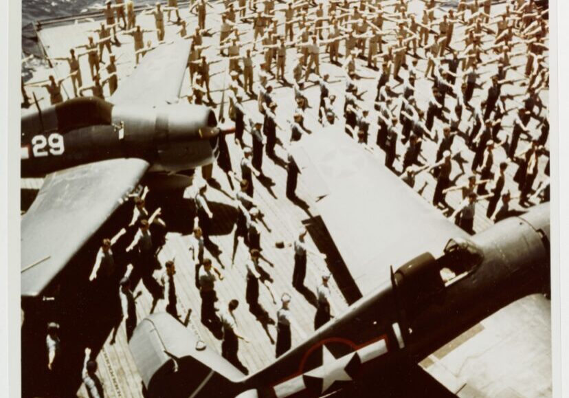 Daily Calisthenics on the flight deck of USS Yorktown CV-10, an Essex class carrier, during the summer of 1943. Planes are Grumman F6F-3 HELLCAT fighters.